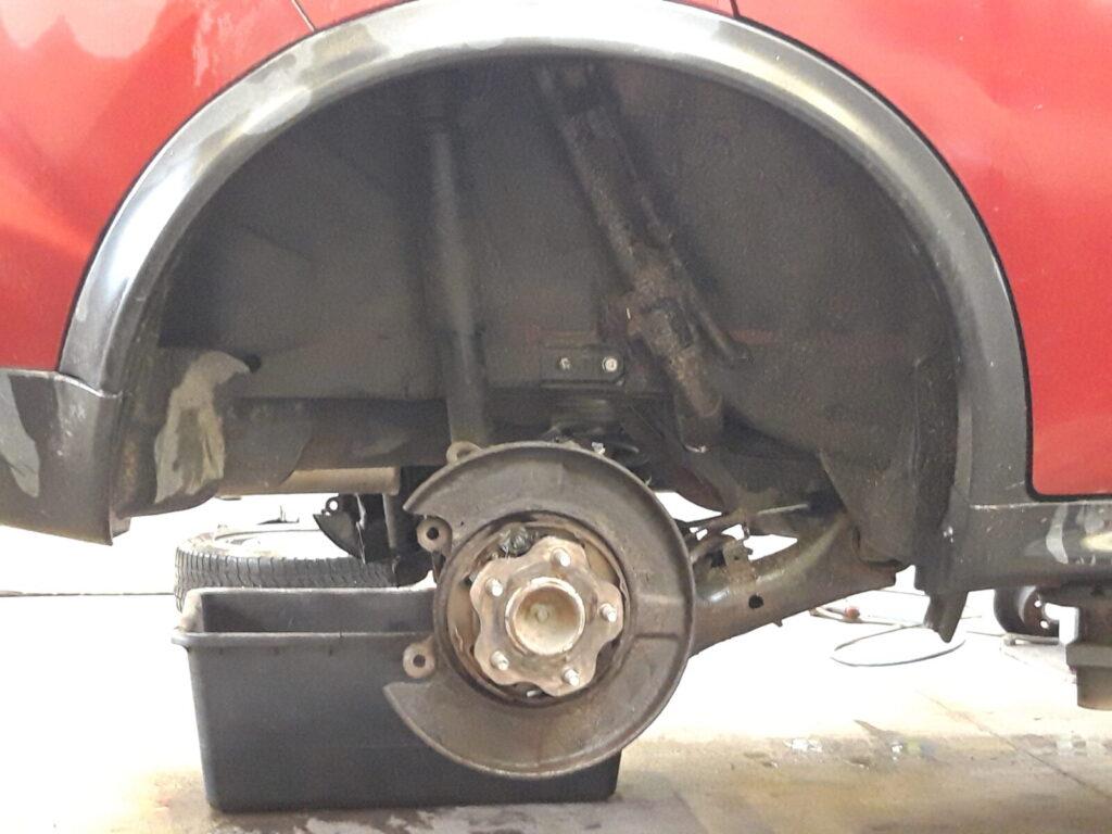 Detailaufnahme eines Autos mit abgenommenem Hinterrad und sichtbarem Bremssystem