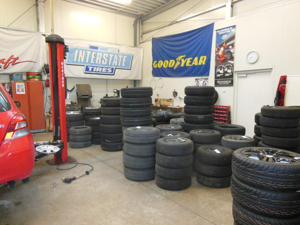 Reifenlager in einer Autowerkstatt mit verschiedenen Reifenstapeln und Werkstattausrüstung